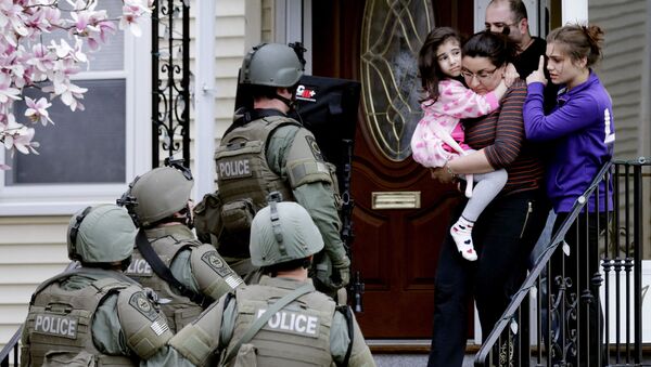 In this April 19, 2013, file photo, a woman carries a girl from their home as a SWAT team searching for a suspect in the Boston Marathon bombings enters the building in Watertown, Mass. - Sputnik International