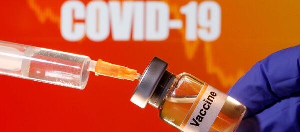 A small bottle labeled with a Vaccine sticker is held near a medical syringe in front of displayed Coronavirus COVID-19 words in this illustration taken April 10, 2020. A small bottle labeled with a Vaccine sticker is held near a medical syringe in front of displayed Coronavirus COVID-19 words in this illustration taken April 10, 2020. - Sputnik International