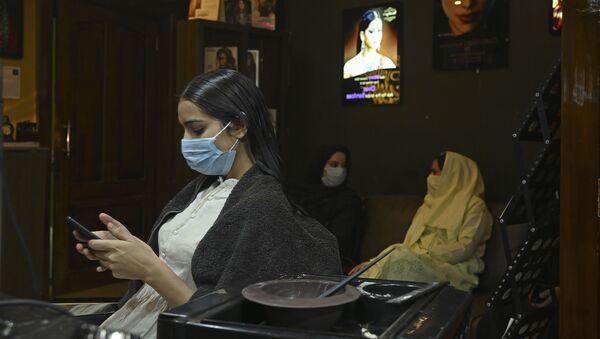 A customer wearing a facemask checks a mobile phone at a hair salon, after the government eased a nationwide lockdown as a preventive measure against the COVID-19 coronavirus, in Srinagar on June 15, 2020 - Sputnik International