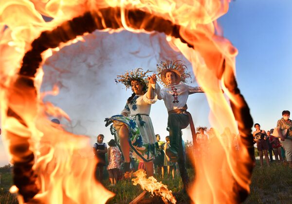 A girl and a young man jump over the fire during the festival of Ivan Kupala on the shore of the Gulf of Pripyat in the ancient Belarusian city of Turov. - Sputnik International