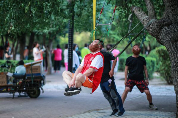 This photo taken on 5 July 2020, shows a man doing exercises as he hangs on a tree in Shenyang in the northeastern Chinese province of Liaoning. - Sputnik International