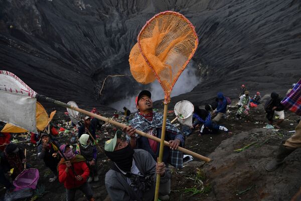 Villagers carry their nets in an attempt to catch coins thrown as offerings by Hindu worshippers into the crater during the Kasada ceremony at Mount Bromo in Probolinggo, East Java Province, Indonesia 7 July 2020. - Sputnik International