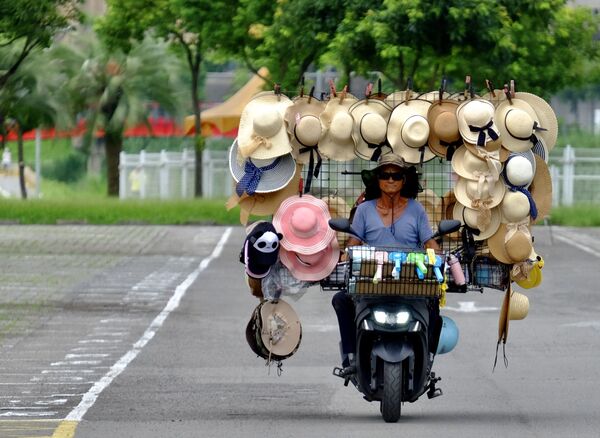 Wang Shang-chi, 75, a mobile hat vender, rides his bike in a parking lot next to the Taipei City Zoo on 9 July 2020. - Sputnik International