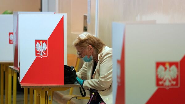 A voter sits behind a voting booth on July 12, 2020 in Warsaw during the second round of Poland's presidential election. - Poles began voting on on July 12, 2020 in a knife-edge presidential election between a populist incumbent closely allied with the US President and a europhile liberal who wants to restore ties with Brussels.  - Sputnik International
