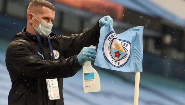 A member of the ground staff spray the corner flag during the English Premier League football match between Manchester City and Arsenal at the Etihad Stadium in Manchester, north west England, on June 17, 2020 - Sputnik International