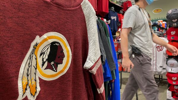 An employee passes a Washington Redskins football shirt for sale at a sporting goods store in Bailey's Crossroads, Virginia, US, 24 June 2020. - Sputnik International