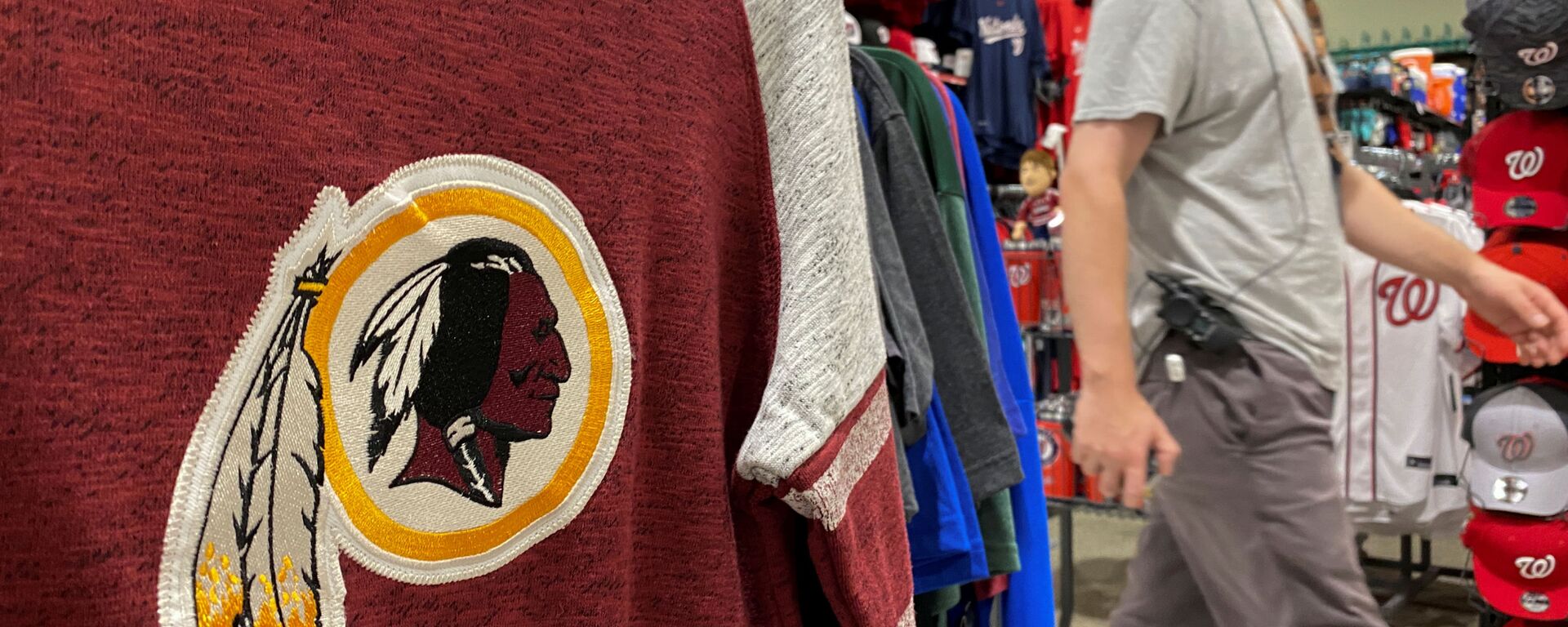 An employee passes a Washington Redskins football shirt for sale at a sporting goods store in Bailey's Crossroads, Virginia, US, 24 June 2020. - Sputnik International, 1920, 13.07.2020