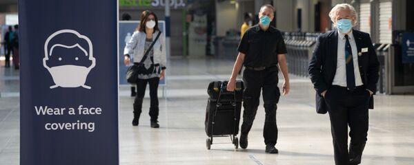 Commuters wearing face masks walk through the concourse at Waterloo Station in London on June 15, 2020 after new rules make wearing face coverings on public transport compulsory while the UK further eases its coronavirus lockdown. - New coronavirus pandemic rules coming into force on June 15 make wearing face coverings such as masks or scarves compulsory on public transport, as various stores and outdoor attractions open for the first time in nearly three months. - Sputnik International