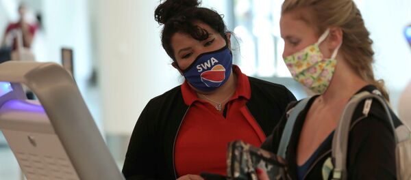 A Southwest Airlines Co. employee wears a protective mask while assisting a passenger at Los Angeles International Airport (LAX) in Los Angeles, California, U.S., May 23, 2020. A Southwest Airlines Co. employee wears a protective mask while assisting a passenger at Los Angeles International Airport (LAX) in Los Angeles, California, U.S., May 23, 2020. - Sputnik International