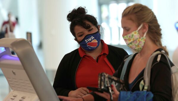 A Southwest Airlines Co. employee wears a protective mask while assisting a passenger at Los Angeles International Airport (LAX) in Los Angeles, California, U.S., May 23, 2020. - Sputnik International