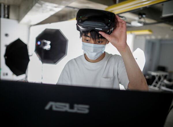 A staff member of Telexistence uses virtual reality technology as he prepares to control the company's shelf-stacking avatar robot, designed to resemble a kangaroo and developed to work in a convenience store, during a photo opportunity ahead of its unveiling in Tokyo, Japan July 3, 2020.  - Sputnik International