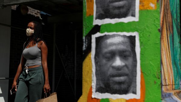 A woman walks with a protective face covering past a mural of George Floyd, in the aftermath of his death in Minneapolis police custody, along 125th street in the Harlem neighborhood of  New York City, New York, U.S., July 9, 2020. - Sputnik International