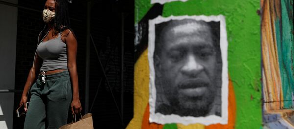 A woman walks with a protective face covering past a mural of George Floyd, in the aftermath of his death in Minneapolis police custody, along 125th street in the Harlem neighborhood of  New York City, New York, U.S., July 9, 2020. - Sputnik International
