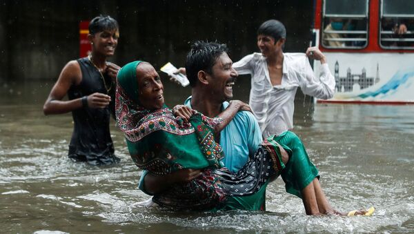 A man carries an elderly woman as they cross a waterlogged street during heavy rainfall in Mumbai, India, July 15, 2020 - Sputnik International