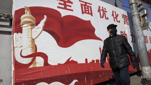 A resident wearing mask walks past government propaganda calling for refinement of the business environment to aid the economic development of the capital in Beijing on Tuesday, March 3, 2020 - Sputnik International