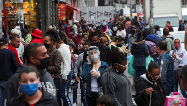 A woman wearing a protective mask and a face shield talks on the phone as people walk at a popular shopping street amid the outbreak of the coronavirus disease (COVID-19), in Sao Paulo, Brazil, July 15, 2020. - Sputnik International