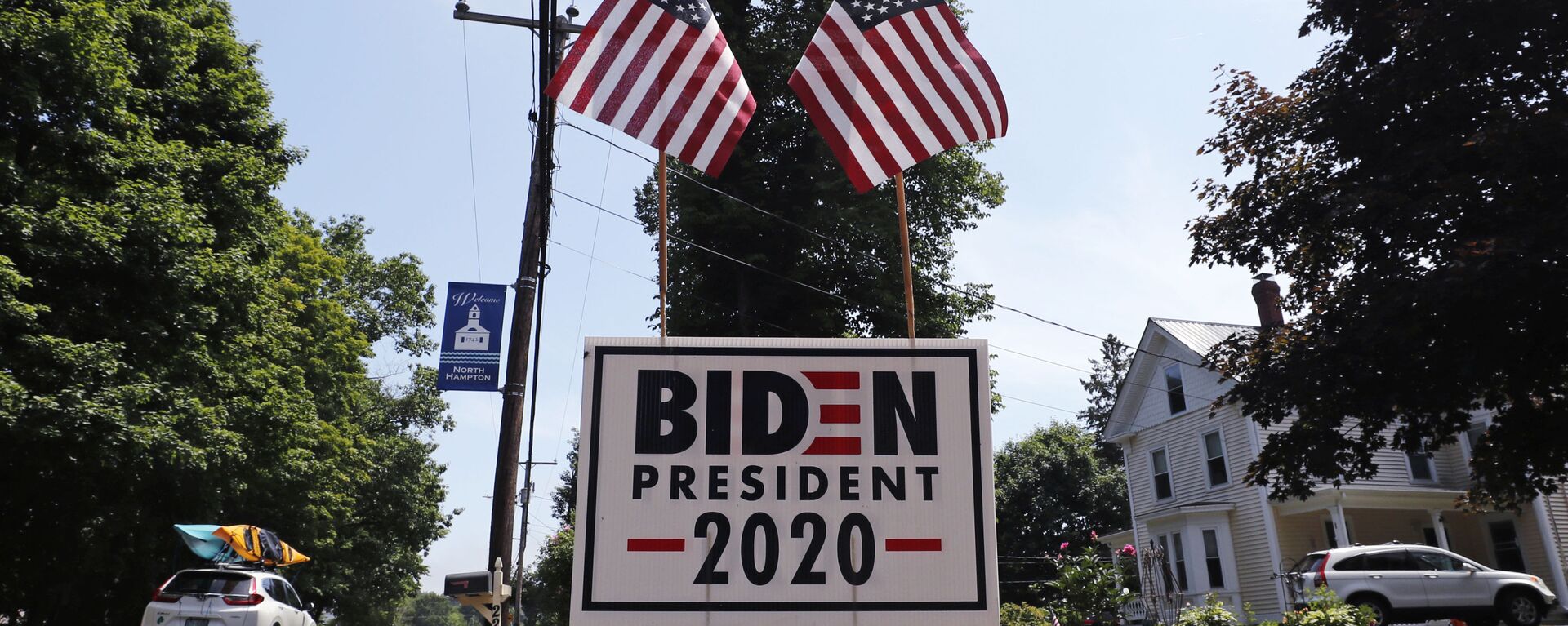 In this June 23, 2020, file photo, a car passes a yard displaying a campaign sign for Democratic presidential candidate, former Vice President Joe Biden in North Hampton, New Hampshire. The coronavirus pandemic isn't going away anytime soon, but campaigns are still forging ahead with in-person organizing. The pandemic upended elections this year, forcing campaigns to shift their organizing activities almost entirely online and compelling both parties to reconfigure their conventions.  - Sputnik International, 1920, 26.01.2023