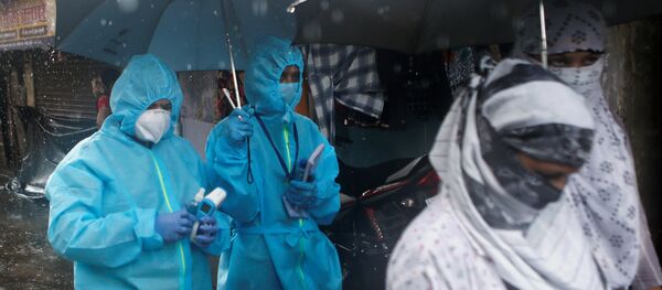 A health worker in personal protective equipment (PPE) walks holding an umbrella on a rainy day during a check up campaign for the coronavirus disease (COVID-19) in Mumbai, India, July 14, 2020 - Sputnik International