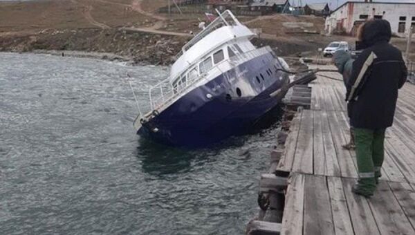 A vessel heeled due to a storm at the pier in the village of Khuzhir - Sputnik International