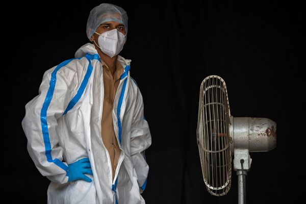 A health worker in personal protective equipment (PPE) takes a break while waiting for people to collect samples to conduct tests for the coronavirus disease (COVID-19), amid the spread of the disease, in New Delhi, India July 10, 2020 - Sputnik International