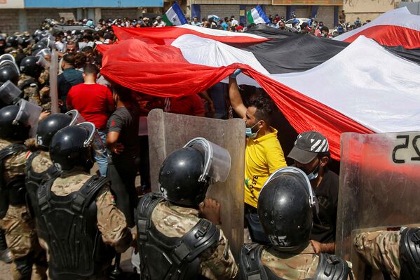 Iraqi security forces stand in front of demonstrators in anti-government protests during Iraqi Prime Minister Mustafa al-Kadhimi's visit, in Basra, Iraq, July 15, 2020 - Sputnik International