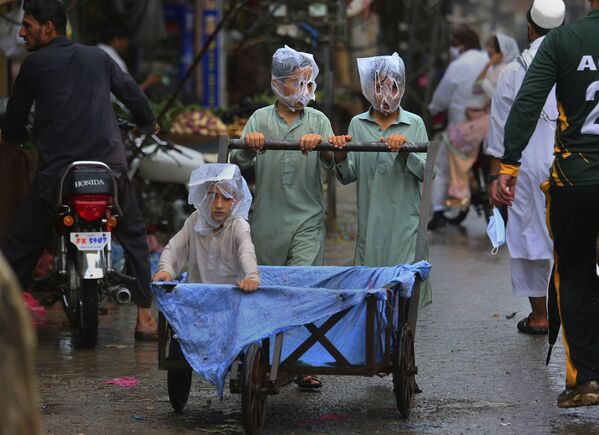 Youths cover their faces with plastic bags while pushing a handcart during rainfall in Peshawar, Pakistan, Sunday, July 12, 2020 - Sputnik International