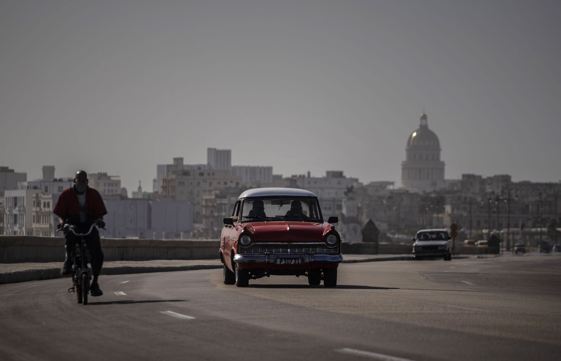 An American classic car and bicycle share the road on the Malecon amid a cloud of Sahara dust in Havana, Cuba, Thursday, June 25, 2020.  - Sputnik International, 1920, 07.09.2021