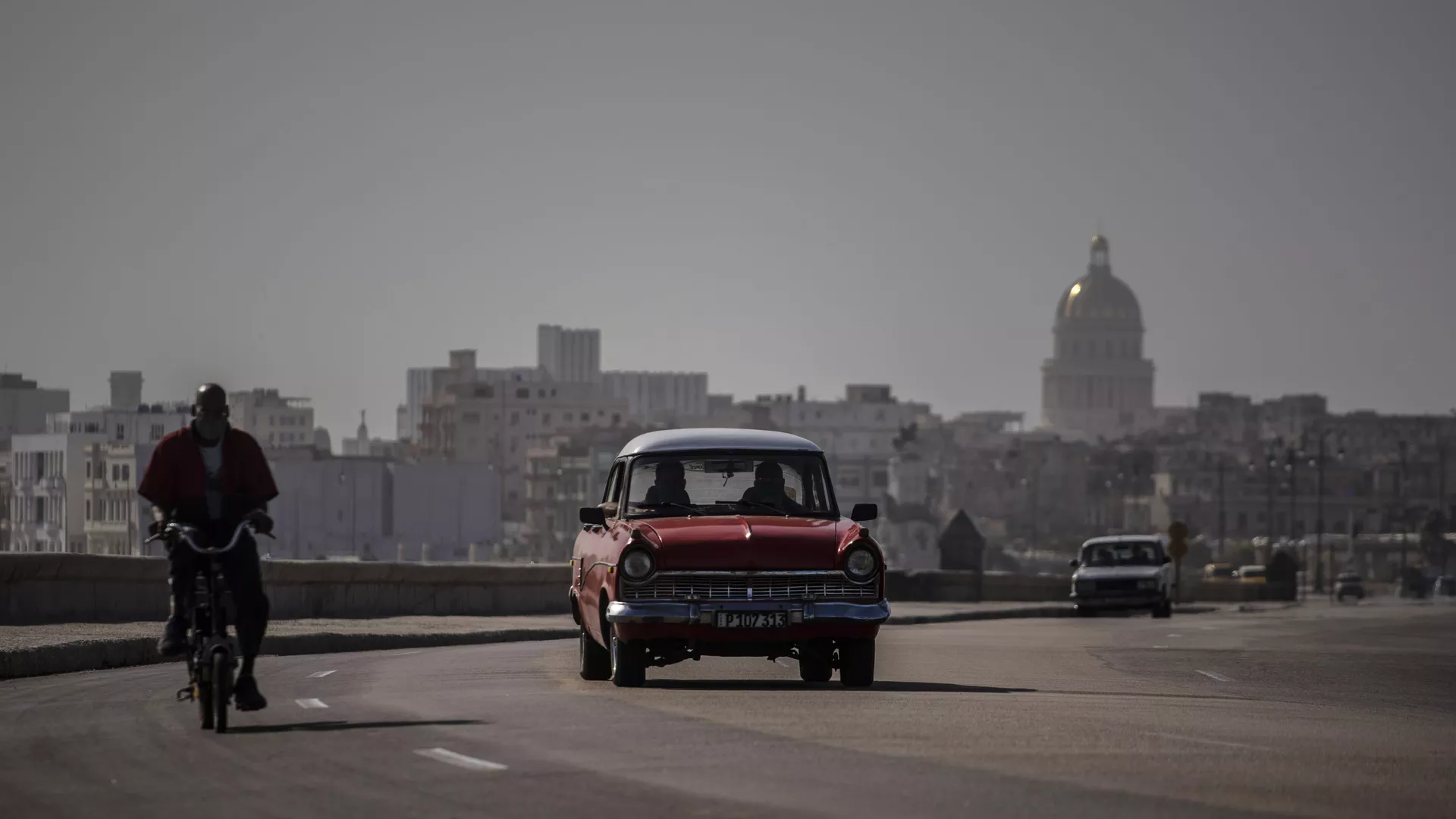 An American classic car and bicycle share the road on the Malecon amid a cloud of Sahara dust in Havana, Cuba, Thursday, June 25, 2020.  - Sputnik International, 1920, 20.10.2024