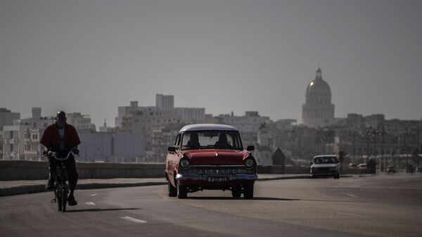 An American classic car and bicycle share the road on the Malecon amid a cloud of Sahara dust in Havana, Cuba, Thursday, June 25, 2020.  - Sputnik International