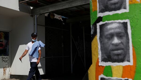 A man walks by a mural of George Floyd, in the aftermath of his death in Minneapolis police custody, along 125th street in the Harlem neighborhood of  New York City, New York, U.S., July 9, 2020. - Sputnik International