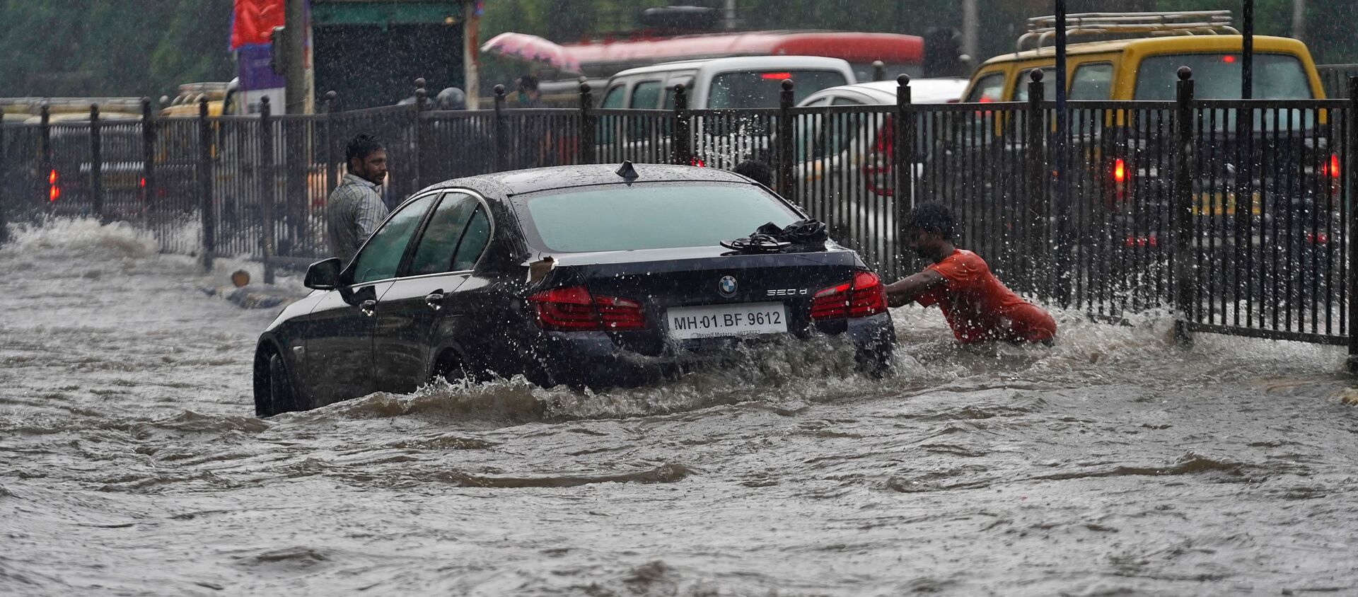 A man pushes a car, stuck in a flooded road, during heavy rains in Mumbai, India - Sputnik International, 1920, 19.07.2020