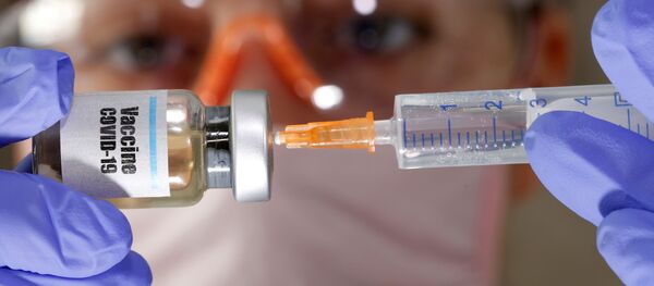  A woman holds a small bottle labeled with a Vaccine COVID-19 sticker and a medical syringe in this illustration taken April 10, 2020 - Sputnik International