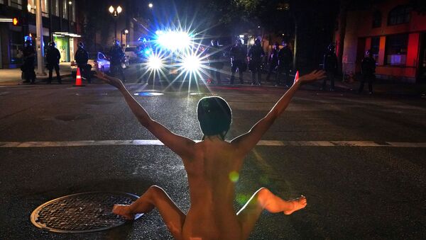 A nude protester faces off against Federal law enforcement officers, deployed under the Trump administration's new executive order to protect federal monuments and buildings, during a protest against racial inequality in Portland, Oregon, U.S. July 18, 2020 - Sputnik International