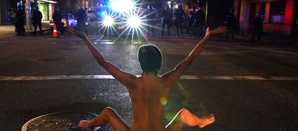 A nude protester faces off against Federal law enforcement officers, deployed under the Trump administration's new executive order to protect federal monuments and buildings, during a protest against racial inequality in Portland, Oregon, U.S. July 18, 2020 - Sputnik International
