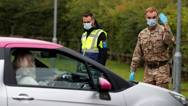 A soldier wearing a protective mask gestures as he directs cars into a coronavirus disease (COVID-19) testing center, as Blackburn with Darwen Council imposes local restrictions in an effort to avoid a local lockdown being forced upon the area, amid the coronavirus disease (COVID-19) outbreak, in Blackburn, Britain July 16, 2020 - Sputnik International