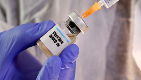 FILE PHOTO: A woman holds a small bottle labeled with a Vaccine COVID-19 sticker and a medical syringe in this illustration taken April 10, 2020 - Sputnik International
