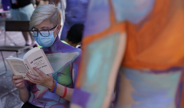 A woman reads a book wearing a mask as she gets her body painted during the 7th annual NYC Bodypainting Day in Times Square 24 July 2020. - Sputnik International