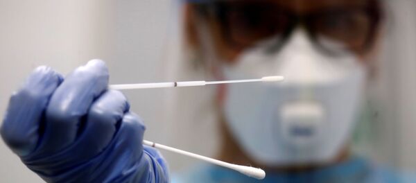 A retired doctor who volunteered to work at the new Duesseldorf Airport Corona Test Centre holds a test stick before a voluntary coronavirus disease A retired doctor who volunteered to work at the new Duesseldorf Airport Corona Test Centre holds a test stick before a voluntary coronavirus disease - Sputnik International