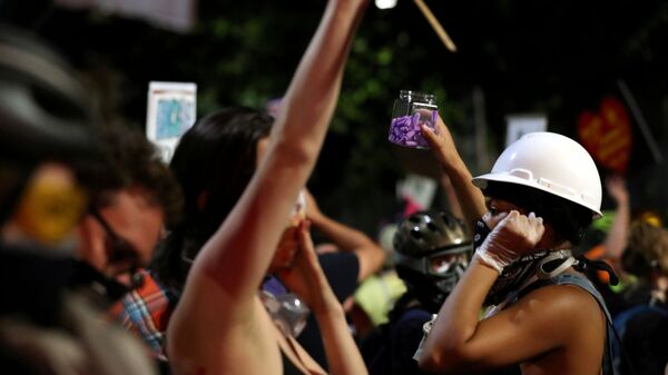 A demonstrator hands out earplugs to fellow protesters to block out the sounds from flashbangs used by security forces, at a protest against racial inequality and police violence in Portland, Oregon, U.S., July 26, 2020. - Sputnik International