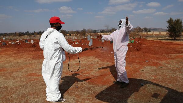 Funeral workers wearing personal protective equipment sanitise each other after a burial amid a nationwide coronavirus disease (COVID-19) lockdown, at the Olifantsvlei cemetery, south-west of Joburg, South Africa July 28, 2020. - Sputnik International