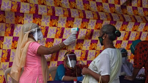 A health worker wearing protective face mask and face shield checks the temperature of a resident during a check-up campaign for the coronavirus disease (COVID-19) in Mumbai, India, July 22, 2020 - Sputnik International
