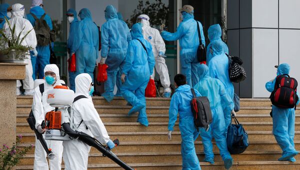 Vietnamese construction workers in blue protective suits infected with the coronavirus disease (COVID-19) arrive at the tropical diseases hospital after being repatriated from Equatorial Guinea via a specially-adapted Vietnam Airlines plane filled with medical equipment and negative pressure chambers, in Hanoi, Vietnam July 29, 2020 - Sputnik International