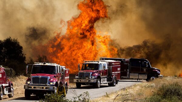 Flames flare behind fire trucks at the Apple Fire in Cherry Valley, Calif., Saturday, Aug. 1, 2020. A wildfire northwest of Palm Springs flared up Saturday afternoon, prompting authorities to issue new evacuation orders as firefighters fought the blaze in triple-degree heat - Sputnik International