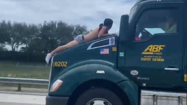 A screenshot from a video of a bloodied man clinging to the hood of a double-trailer semi-truck travelling on a Florida highway for some 9 miles (14.5 kilometers), 1 August 2020. - Sputnik International