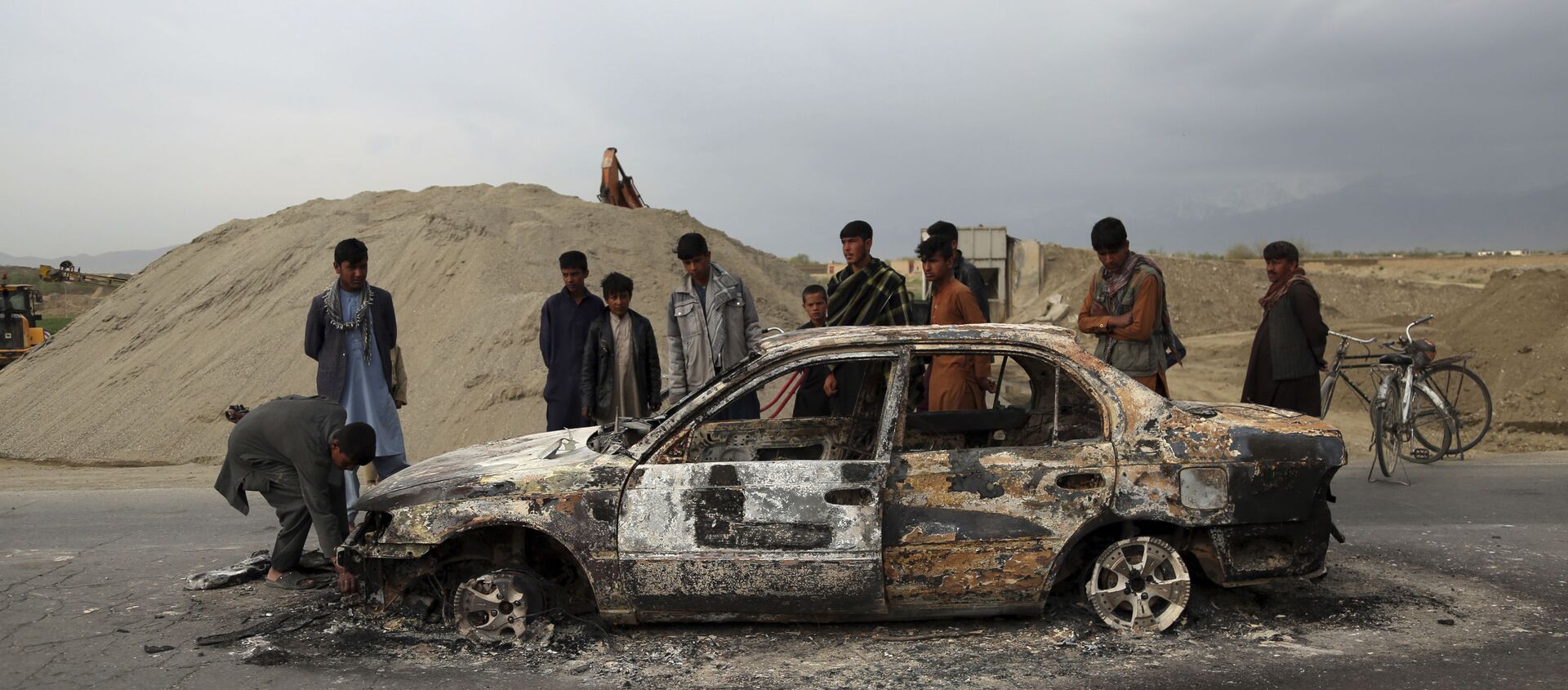 In this April 9, 2019, file photo, Afghans watch a civilian vehicle burnt after being shot by U.S. forces following an attack near the Bagram Air Base, north of Kabul, Afghanistan. Three American service members and a U.S. contractor were killed when their convoy hit a roadside bomb on Monday near the main U.S. base in Afghanistan, the U.S. forces said. The Taliban claimed responsibility for the attack. Intelligence alleging that Afghan militants might have accepted Russian bounties for killing American troops didn’t scuttle the U.S.-Taliban agreement or President Donald Trump’s plan to withdraw thousands more troops from the war - Sputnik International, 1920, 16.04.2021