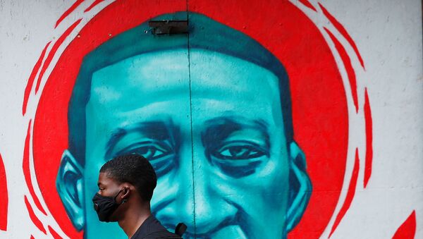 A man wearing a protective mask walks past a mural of George Floyd, in the aftermath of his death in Minneapolis police custody,  in Chicago, Illinois, U.S., July 27, 2020. - Sputnik International