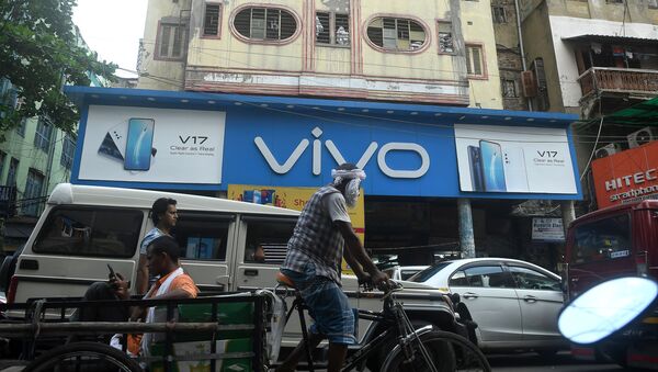 Commuters pass by an advertising board of Chinese mobile phone maker VIVO on a street in Kolkata on June 22, 2020 - Sputnik International