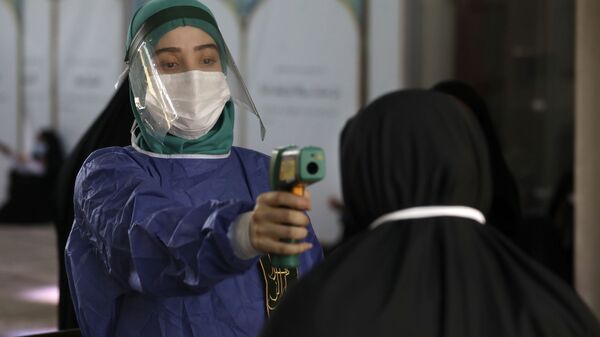 A volunteer wearing protective gear to help prevent the spread of the coronavirus checks temperature of a worshipper as she enters mosque of Tehran University to pray during Arafat Day, Iran, Thursday, July 30, 2020 - Sputnik International