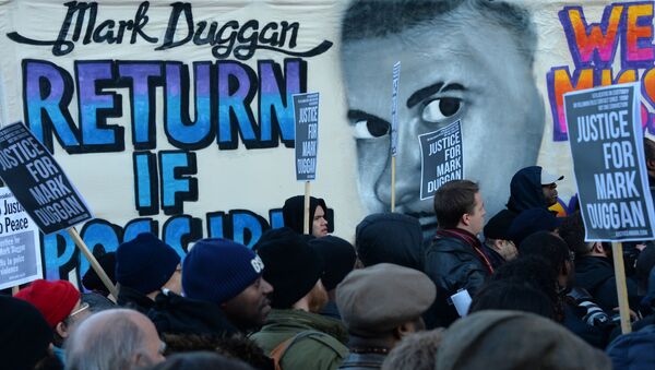People stand beside a banner depicting Mark Duggan, who was shot dead by police, outside Tottenham Police Station in London on January 11, 2014, during a vigil following a jury verdict on January 8, 2014 ruling that Mark Duggan was lawfully killed when he was shot dead by police in August 2011.  - Sputnik International