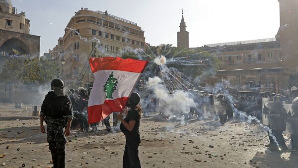 A Lebanese protester waves the national flag during clashes with security forces in downtown Beirut on August 8, 2020, following a demonstration against a political leadership they blame for a monster explosion that killed more than 150 people and disfigured the capital Beirut. - Sputnik International